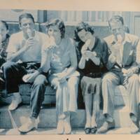 Old picture of people sitting on curb in front of Bardon's